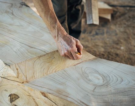 A wood carver is drawing something on the wood