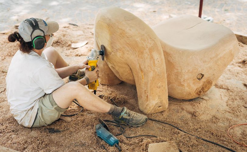 A wood carver is polishing something